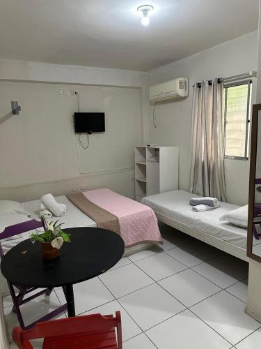 a room with two beds and a table and a tv at Studio 51 residence in Recife