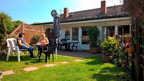 zwei Frauen sitzen an einem Tisch in einem Garten in der Unterkunft Haus Kerstin, Ferienreihenhaus in Westfehmarn
