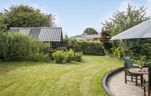 a garden with a table and chairs and an umbrella at 3 Bedroom Beautiful Home In Asperup in Asperup
