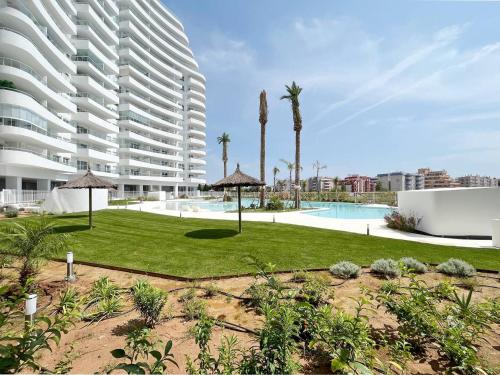 a large apartment building with a lawn and a swimming pool at Luxury Apartment with 2 Bedrooms in Canet d'en Berenguer, Valencia in Canet de Berenguer