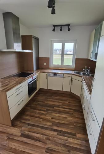 an empty kitchen with white cabinets and wooden floors at Niedergerner Alpaka Ranch Groß in Kemerting