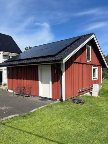 a red barn with a black roof on a yard at Louise guesthouse in Lindome