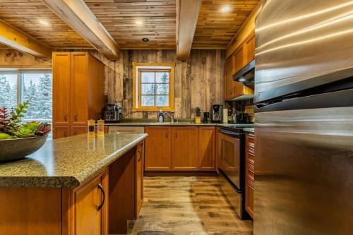 a large kitchen with wooden cabinets andsteel appliances at The Escapade - Private hot tub with pool table in Sainte-Lucie-de-Doncaster