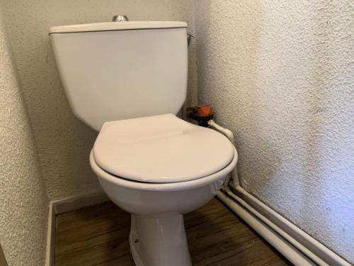 - des toilettes blanches dans un coin de la salle de bains dans l'établissement Résidence Jetay - Appartement chaleureux pour 4 aux Ménuires MAE-5644, aux Menuires