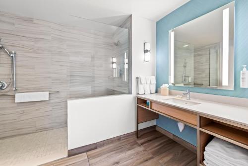 a bathroom with a tub and a sink and a mirror at Hilton Garden Inn Seattle North/Everett in Mukilteo