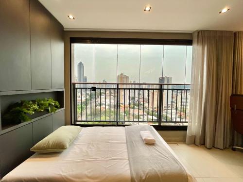 ein Schlafzimmer mit einem Bett und einem großen Fenster in der Unterkunft Luxury Collection Cama Queen e Sofá Cama Separado in Campo Grande