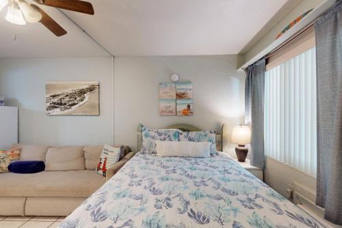 een slaapkamer met een bed en een bank bij Pass-A-Grille Beach Retreat Unit 8 in St Pete Beach