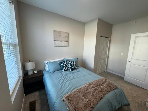 a bedroom with a bed with blue sheets and a window at Unwind in Style at Fargo's Hidden Gem! #102 in Fargo