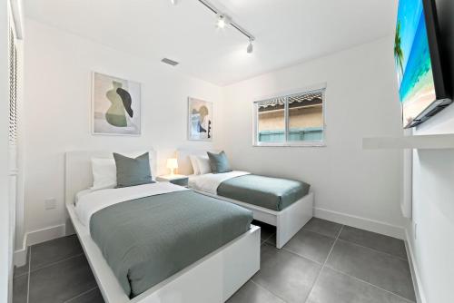 a white bedroom with two beds and a window at Luxurious Family Escape in Hialeah