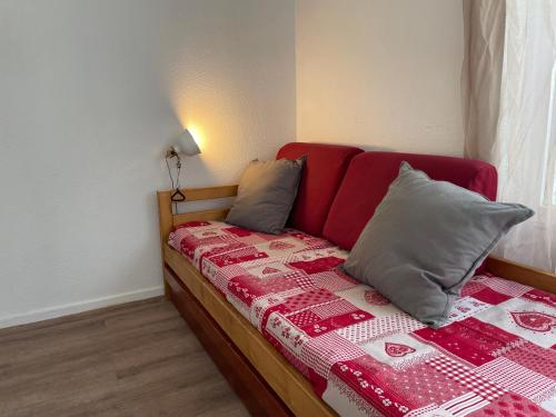 - un lit avec une tête de lit rouge et des oreillers dans l'établissement Studio accès direct à la Croisette, au coeur des Menuires, aux Menuires
