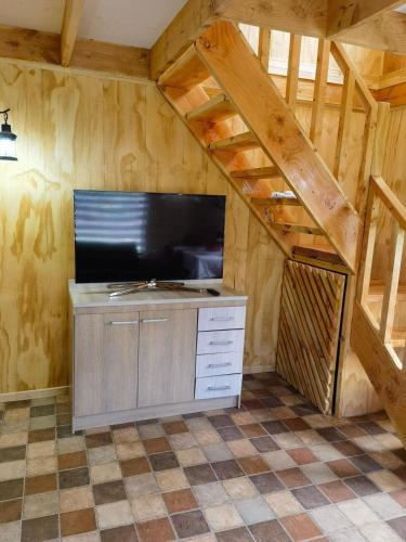 a living room with a tv and a staircase at Cabañas Puntocom in Puerto Aisén