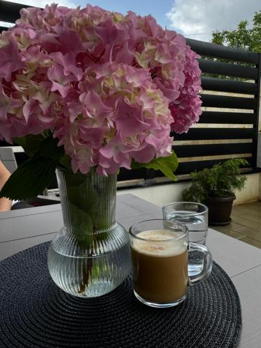 a vase of flowers and a cup of coffee on a table at Apartmani Viver Vrnjačka Banja in Vrnjci