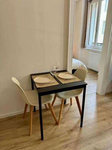 - une table à manger avec 2 chaises et des verres à vin dans l'établissement Le cocon Mulhouse, à Mulhouse