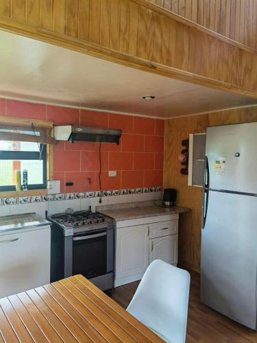 a kitchen with a white refrigerator and a stove at Cabañas Puntocom in Puerto Aisén