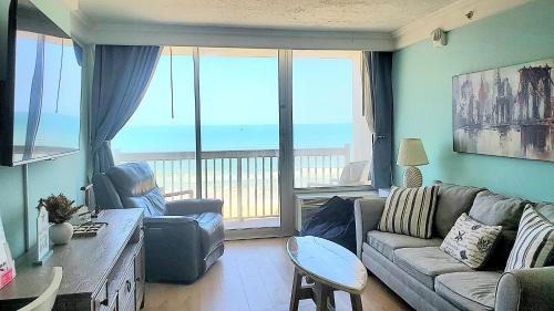 una sala de estar con un sofá y una mesa en Sunkissed-Modern Oceanfront Condo Daytona Beach, en Daytona Beach