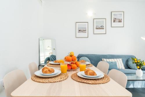 a dining room table with breakfast foods and orange juice at Pool&Beach Apartment Calafell by VM Group in Calafell
