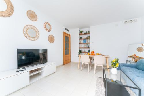 a white living room with a blue couch and a table at Pool&Beach Apartment Calafell by VM Group in Calafell