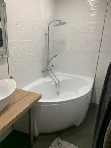 a white bath tub in a bathroom with a sink at Relax apartman in Siófok