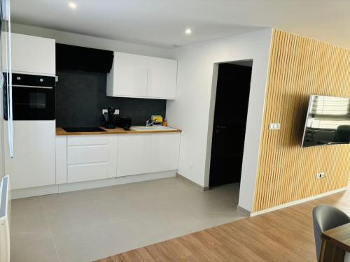 une cuisine avec des armoires blanches et des appareils noirs dans l'établissement Maison de Ville Widensolen - 3 rooms and 3 double beds, à Widensolen