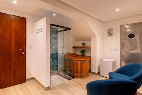 a bathroom with a shower and a blue chair at Pousada Boutique Figueira da Serra in Campos do Jordão