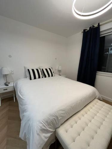 - un lit blanc avec un banc dans une chambre dans l'établissement Charmante maison à louer, à Saint-Cyr-sur-Loire