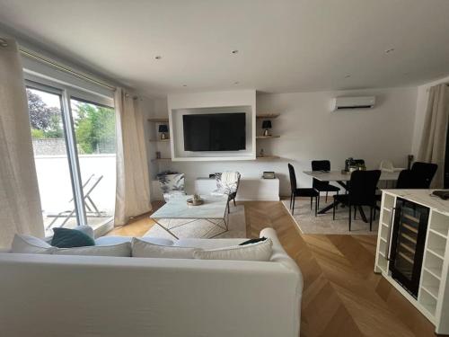 a living room with a white couch and a table at Charmante maison à louer in Saint-Cyr-sur-Loire