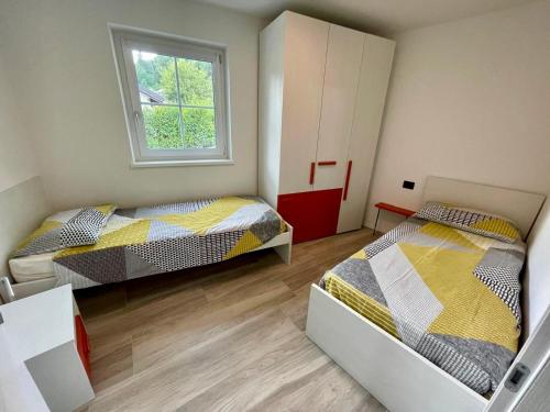 a bedroom with two beds and a window at Appartamento - Chalet Baltmann - Lavarone in Lavarone