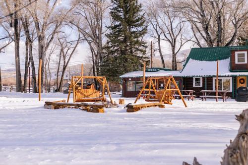 two playground equipment in the snow in front of a building at Chinook Winds Lodge in Dubois