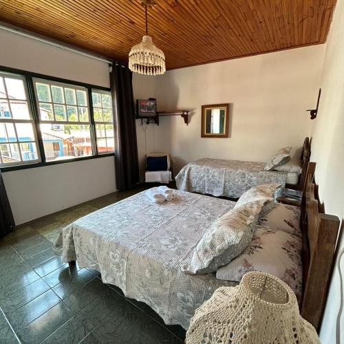a bedroom with two beds and a chandelier at Pousada Sierra in Tiradentes