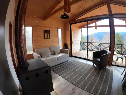 a living room with a couch and a large window at BordeArroyo Malalcahuello in Malalcahuello