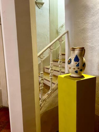 a vase sitting on a yellow stand next to a staircase at Palazzo Palloni: Piano Nobile in Sorano
