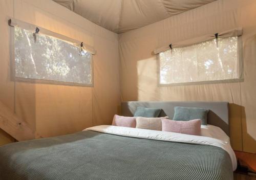 a bed in a small room with two windows at ISOLA VERDE Camping Village in Nettuno