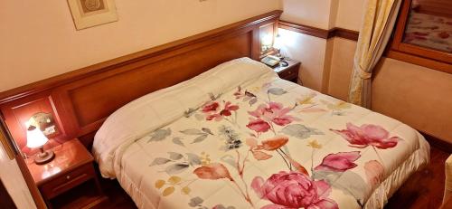a bedroom with a bed with a floral blanket on it at Hotel Minerva in Pordenone