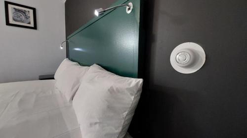 a bed with a white pillow and a light on a wall at Village Motel in Clinton
