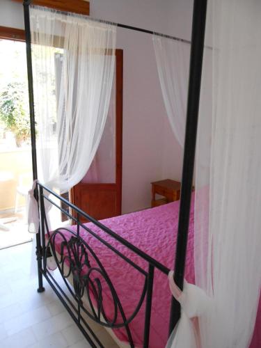 a bedroom with a bed with purple sheets and a window at ANAMAMA -SOCRATES studios in Acharavi