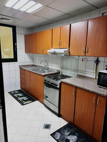 a kitchen with wooden cabinets and a stove top oven at Corniche Street - Extremely Unique Room in Abu Dhabi