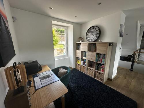 a living room with a table and a clock on the wall at Maison vue Rivière du Bono 8 personnes in Le Bono