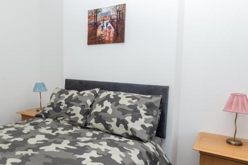 a bedroom with a bed with camouflage sheets and a painting at Sunrise Central in Bexhill
