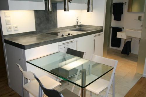 une cuisine avec une table en verre et des chaises blanches dans l'établissement Paris Interiors Rentals - Le Marais LOUVRE - NOTRE DAME, à Paris