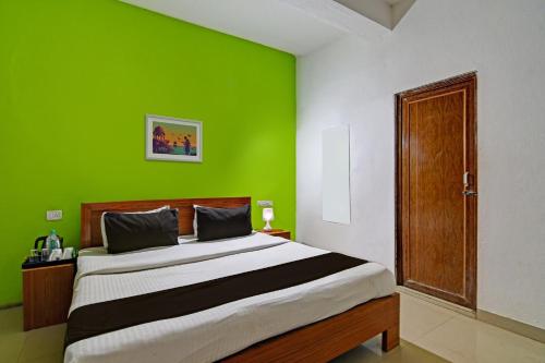 a bedroom with a large bed with a green wall at Hotel O Home Elite Stay Near Shri Shri Shiridi Sai Mandir in Bhubaneshwar