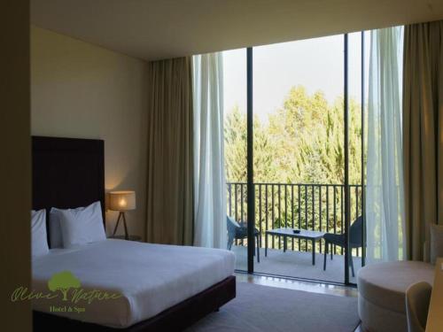a hotel room with a bed and a balcony at Olive Nature Hotel & SPA - Quinta Valle de Passos in Valpaços