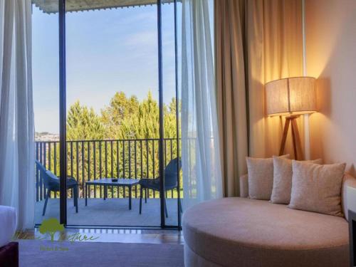 a bedroom with a bed and a balcony with a table and chairs at Olive Nature Hotel & SPA - Quinta Valle de Passos in Valpaços