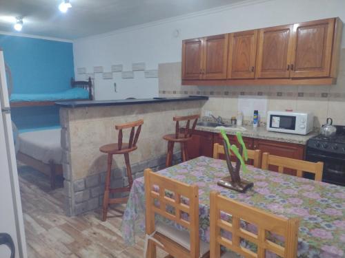 a kitchen with a table and chairs and a kitchen with a bed at Cabañas y Bungalow " La Comarca" in Concepción del Uruguay