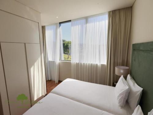 a hotel room with a bed and a large window at Olive Nature Hotel & SPA - Quinta Valle de Passos in Valpaços