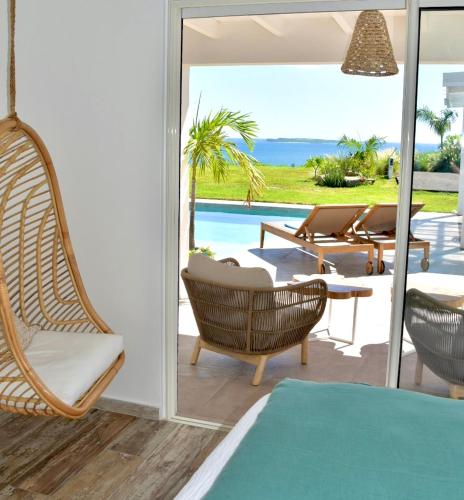 a room with chairs and a patio with a view of the ocean at SUNSEEKER SXM - Luxury Guest House 4 stars - Amazing Sea View Pinel - Tintamarre in Orient Bay