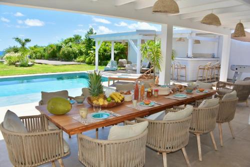 a dining room with a table and chairs and a pool at SUNSEEKER SXM - Luxury Guest House 4 stars - Amazing Sea View Pinel - Tintamarre in Orient Bay
