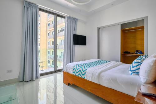 a bedroom with a bed and a large window at Monaco Residences Piantini in Santo Domingo