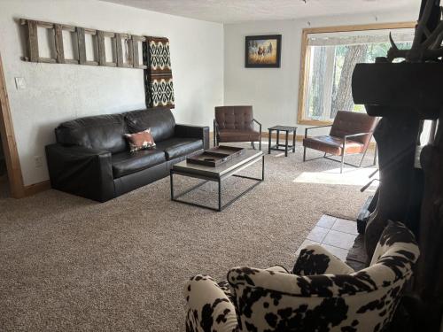 a living room with a black leather couch and chairs at Chinook Winds Lodge in Dubois