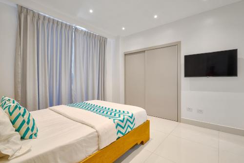 a bedroom with a bed and a flat screen tv at Monaco Residences Piantini in Santo Domingo