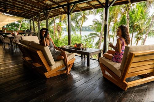 three girls sitting on chairs on a porch with a table at Bocas Sunset Beach House in Bocas del Toro